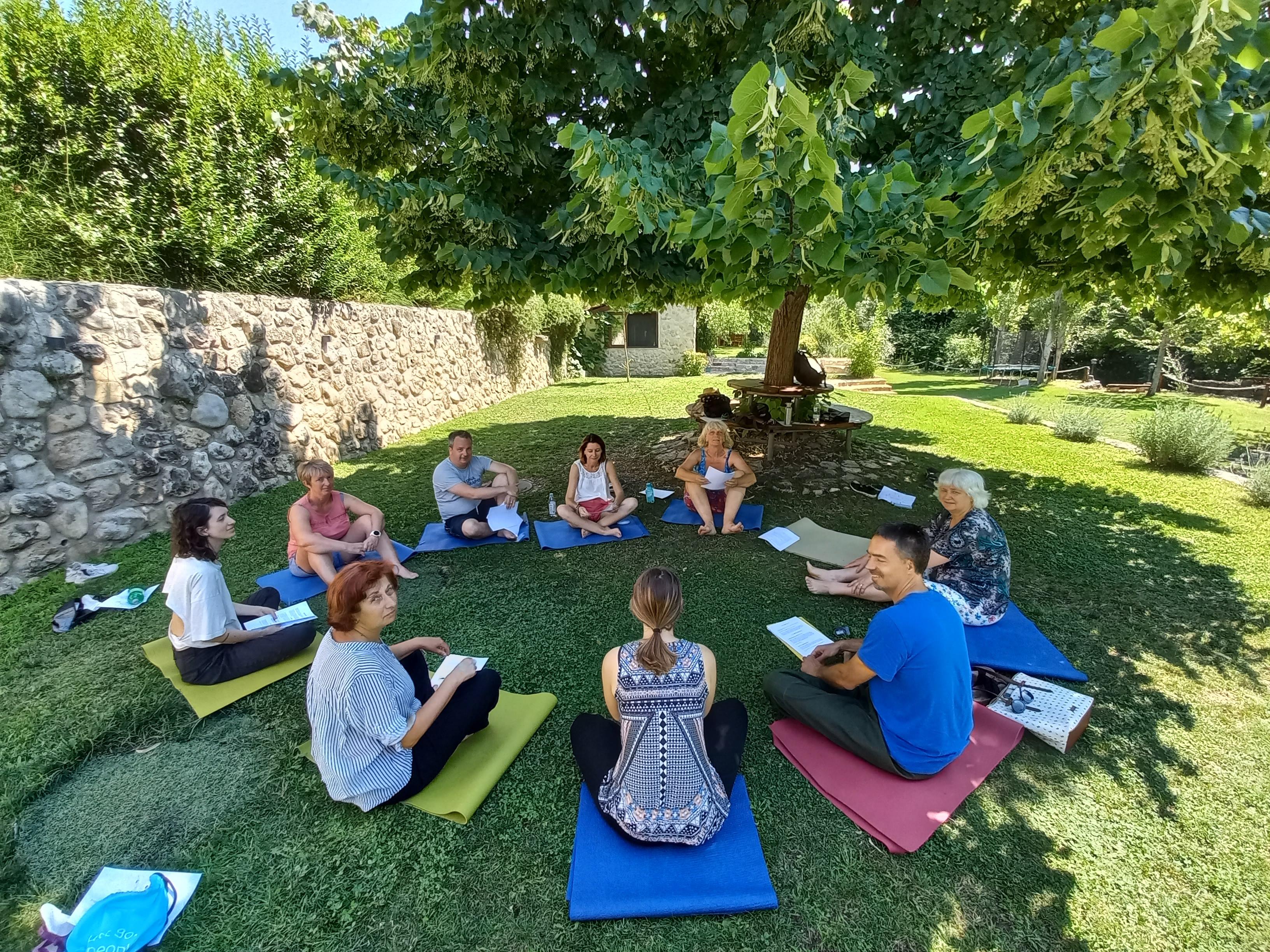 Vairāki skolotāji sēž uz zāles aplī un mācās ārā